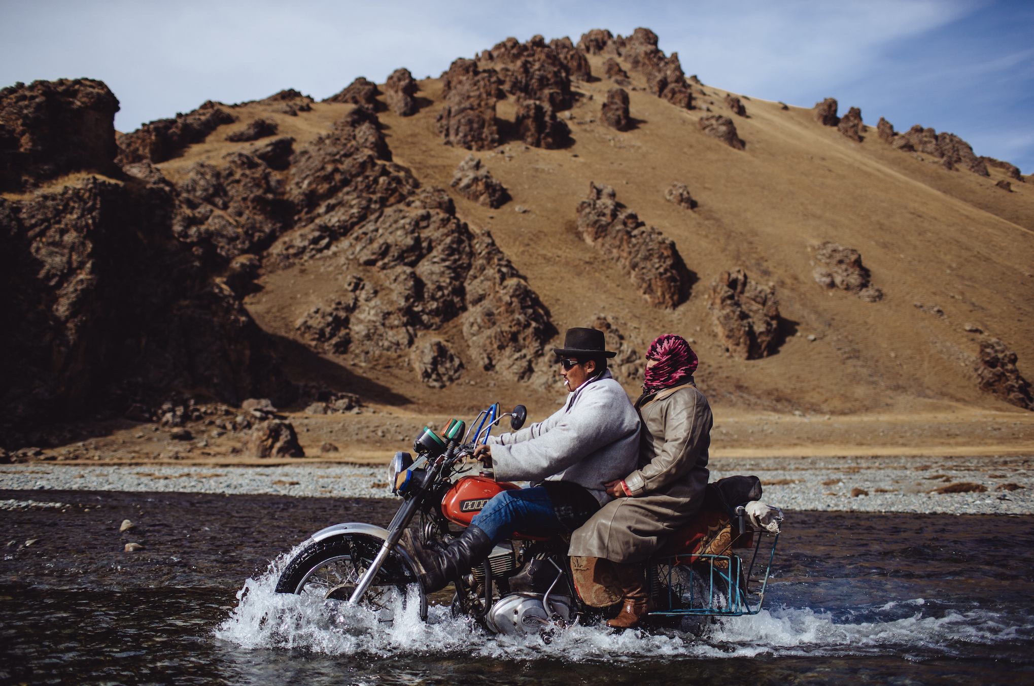 "Couple Crossing a Creek Riding a Russian Classic IZH Motorcycle  in the Khaingain Nuruu National Park 50km North of Erdenetsogt, Mongolia" 